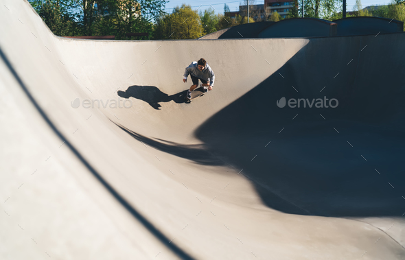 Skater making slope ridding skateboard on bowl ramp