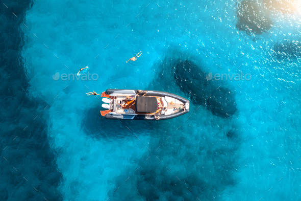 Aerial view of motorboat, swimming people in blue sea at sunset - Stock Photo - Images