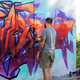A street artist paints colored graffiti on the wall of a public space. - PhotoDune Item for Sale