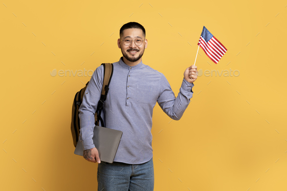 Student Exchange Concept. Young Asian Man Holding Laptop And American Usa Flag