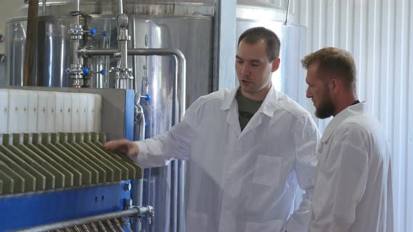 Beer Production. Two Workers in White Coats Are Meeting