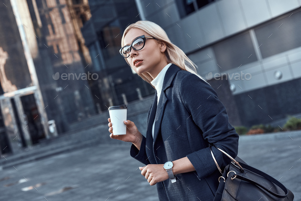 Serious female officer worker walking on street of downtown with