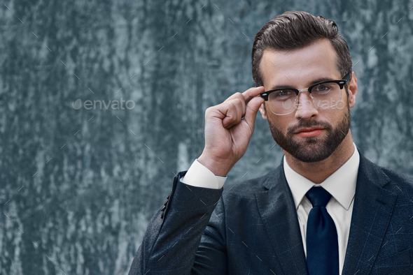Young businessman looking into the distance holding one-handed glasses - Stock Photo - Images