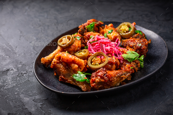 Grilled Lemon and garlic chicken wings with pickled root vegetables and jalapenos.  - Stock Photo - Images