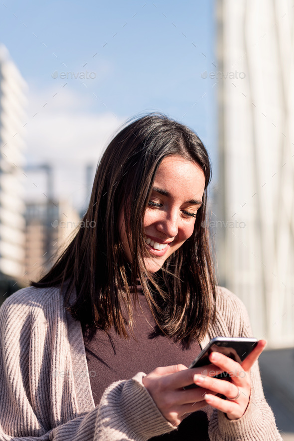 woman smiling happy while using her mobile phone - Stock Photo - Images