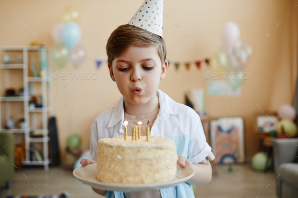 Cute boy holding birthday cake and blowing candles Stock Photo by ...