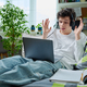 Young guy in headphones using laptop for video communication, lying at home - PhotoDune Item for Sale