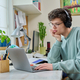 Young male college student sitting at desk at home using laptop - PhotoDune Item for Sale
