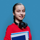Portrait of smiling high school student girl with textbooks on blue background - PhotoDune Item for Sale