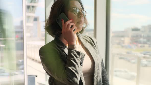 Business woman talking on the phone in a modern office. Successful woman communicates with client. alt