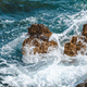 Ocean waves braking at coastline rocks covering them in white sea foam on sunny summer day - PhotoDune Item for Sale