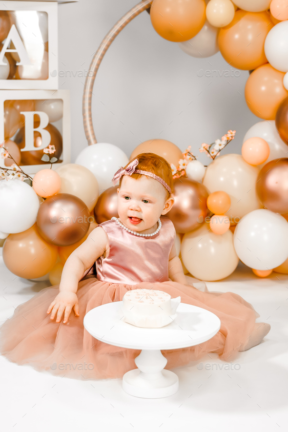 Little redhead baby girl celebrates first birthday. Cake crash smash, hands eating. 1 year family  - Stock Photo - Images