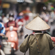 Person with traditional conical hat against traffic motorbikes on busy street - PhotoDune Item for Sale