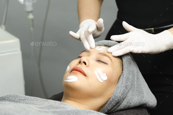 Young woman getting facial mask by professionals in beauty clinic. - Stock Photo - Images