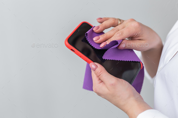 Germs elimination. Cleaning the smartphone screen with fiber cloth from dirt dust and other external - Stock Photo - Images