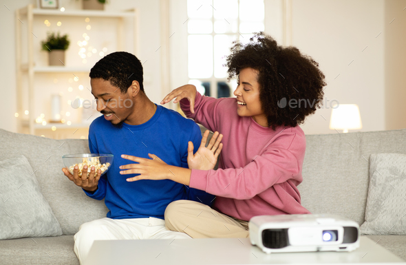 Happy African Couple Watching Film Via Projector Fooling At Home