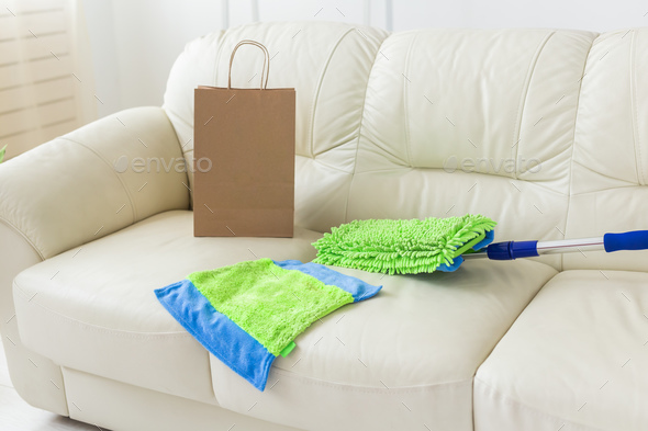 Blue and green plastic mop with adjustable handle lying on couch - tools for cleaning services and - Stock Photo - Images