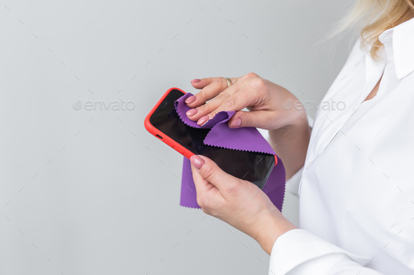 Closeup woman hands cleaning the smartphone screen with a fiber cloth from dirt dust and virus - Stock Photo - Images