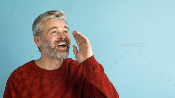 Happy middle aged man holding hand next to mouth, screaming - Stock Photo - Images