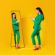 Trendy lady pointing at her reflection in mirror posing after successful shopping, wearing green - PhotoDune Item for Sale