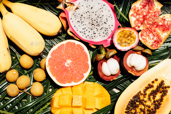 Fresh exotic fruits on green tropical palm leaves background - papaya, mango, pineapple, passion - Stock Photo - Images