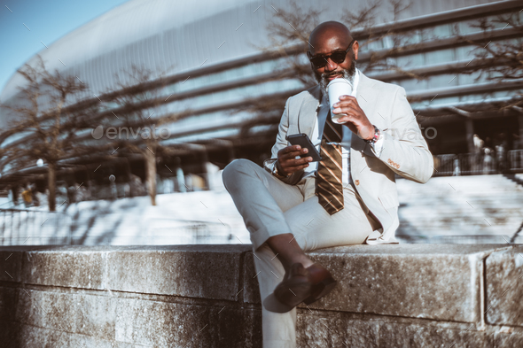 Black man driking coffee while texting - Stock Photo - Images