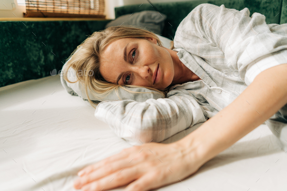 Portrait of a woman waking up early in the morning, lying on the bed. - Stock Photo - Images