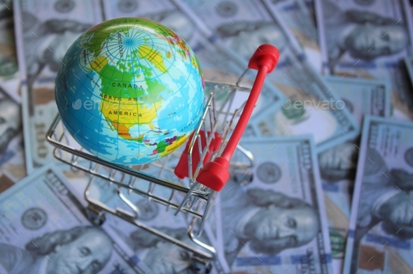 Earth globe inside shopping trolley on top of money.