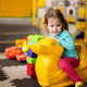 Baby girl swings on yellow paralon duck at kindergarten. - PhotoDune Item for Sale