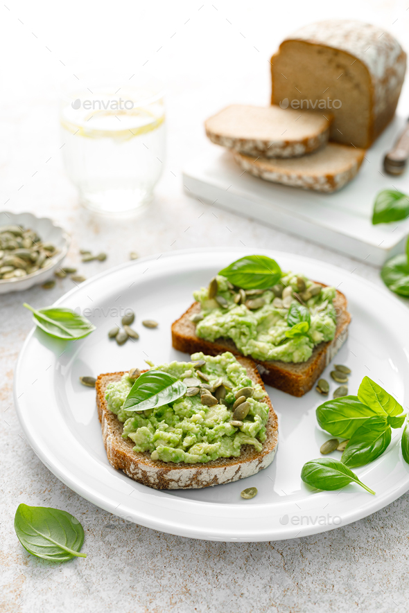 Avocado sandwich with pumpkin seeds. Healthy vegetarian avocado toast with rye bread for breakfast - Stock Photo - Images