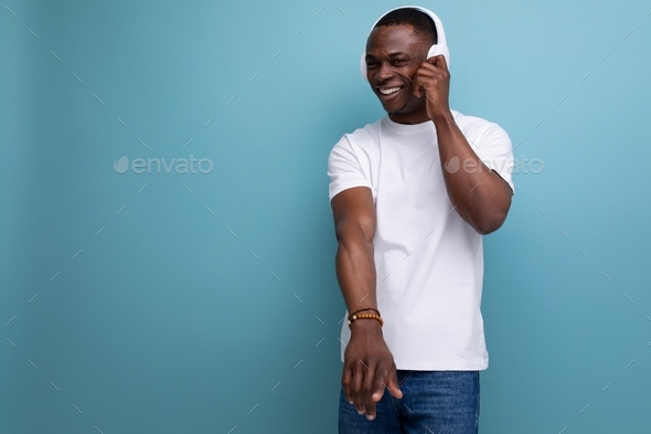 well-groomed handsome young african guy dancing to music in headphones