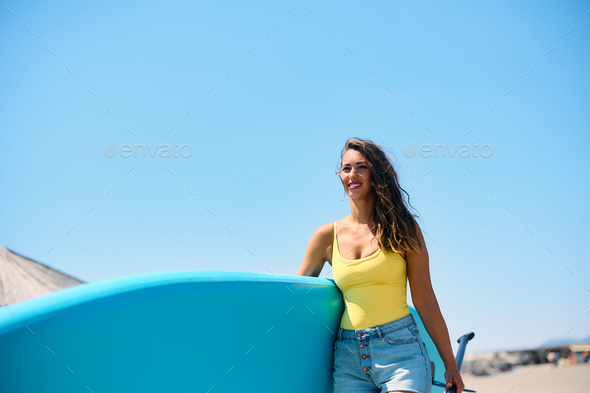Happy woman with paddleboard going on the beach while enjoying in summer day at the sea. - Stock Photo - Images