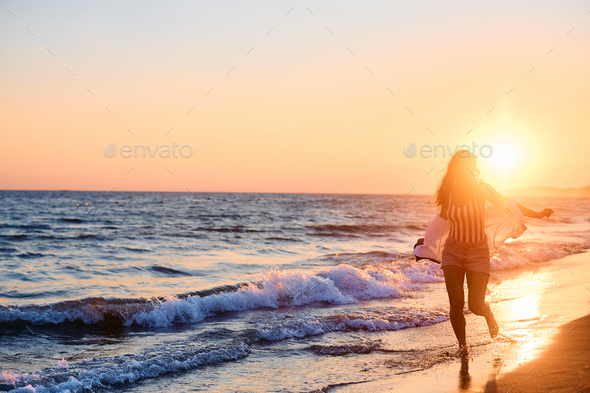 Carefree woman running on the beach at sunset. - Stock Photo - Images