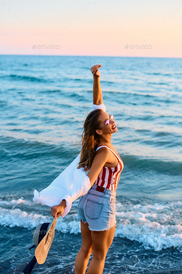 Young woman enjoying in freedom and summer breeze on the beach. - Stock Photo - Images