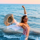 Young woman with raised arms on the beach at sunset. - PhotoDune Item for Sale