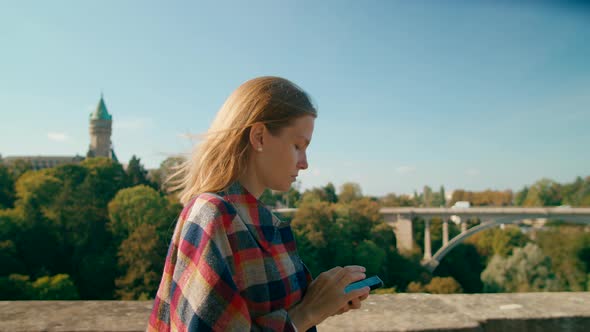 Young European Woman Texting on Mobile App Using Smartphone in Luxembourg City