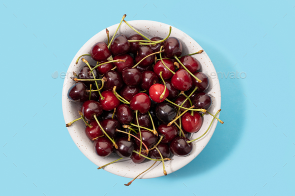 Fresh sweet cherries bowl isolated on blue background - Stock Photo - Images