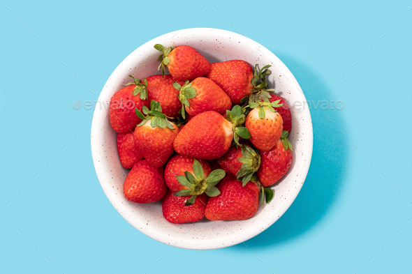 Fresh strawberries in bowl isolated on blue background - Stock Photo - Images