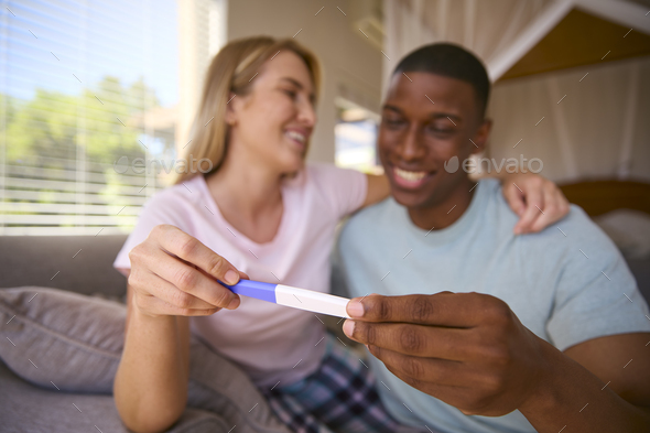 Excited Multi-Racial Couple In Bedroom At Home Celebrating Positive Pregnancy Test Result - Stock Photo - Images