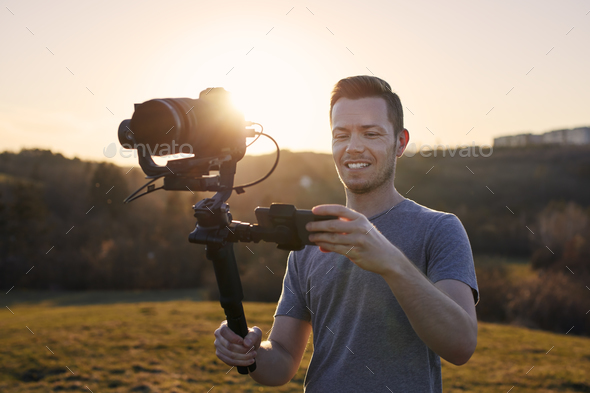 Portrait of happy videographer with camera and gimbal - Stock Photo - Images