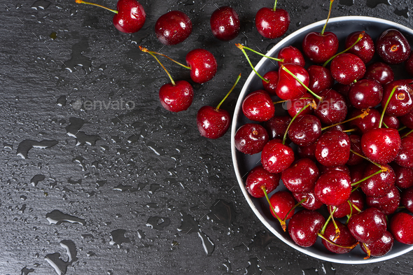 Fresh red ripe sweet cherry with water drops on plate on black slate background. - Stock Photo - Images