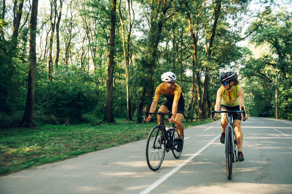 Couple riding bicycles outside of the city and wearing helmets and sunglasses - Stock Photo - Images