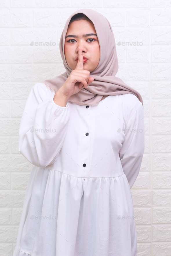 Young Asian Muslim woman in hijab showing keep silence sign - Stock Photo - Images