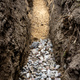 A trench dug in the yard along the fence to lay the drainage pipe,visible gravel and yellow sand. - PhotoDune Item for Sale
