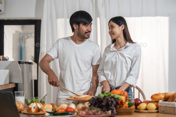 Happy smiling couple cooking together and healthy eating concept - couple cooking food at home - Stock Photo - Images