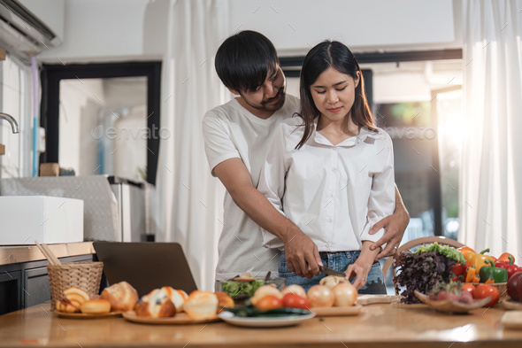 Happy couple cooking together and healthy eating concept - couple cooking food at home kitchen - Stock Photo - Images