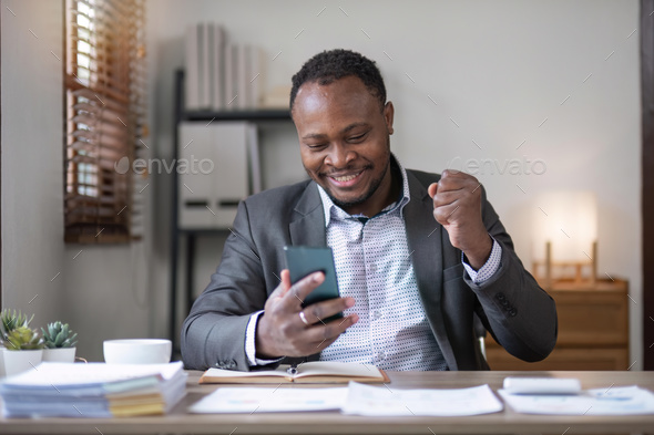 Handsome young businessman celebrating success with arms raised received a good message or news on - Stock Photo - Images