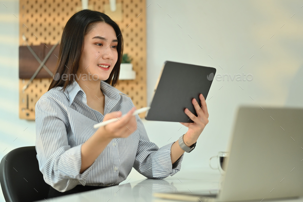 Smiling millennial female entrepreneur communicating online at workstation. - Stock Photo - Images