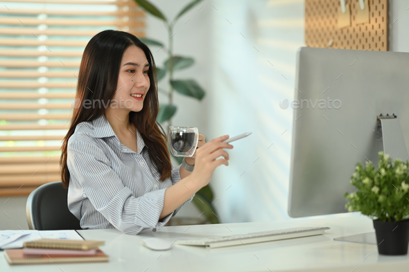 Attractive millennial female entrepreneur analyzing statistics data online on computer screen. - Stock Photo - Images