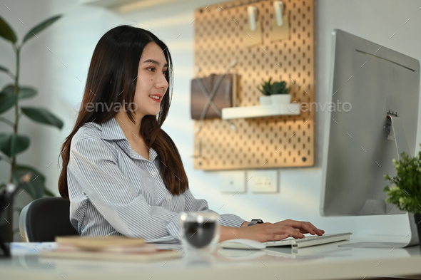 Satisfied small business entrepreneur looking at computer monitor watching online webinars - Stock Photo - Images